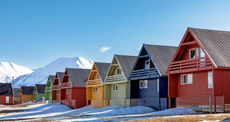 Maisons colorées avec des montagnes enneigées en arrière-plan.