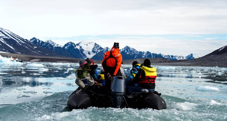 Des gens dans un bateau naviguant dans des eaux glacées.