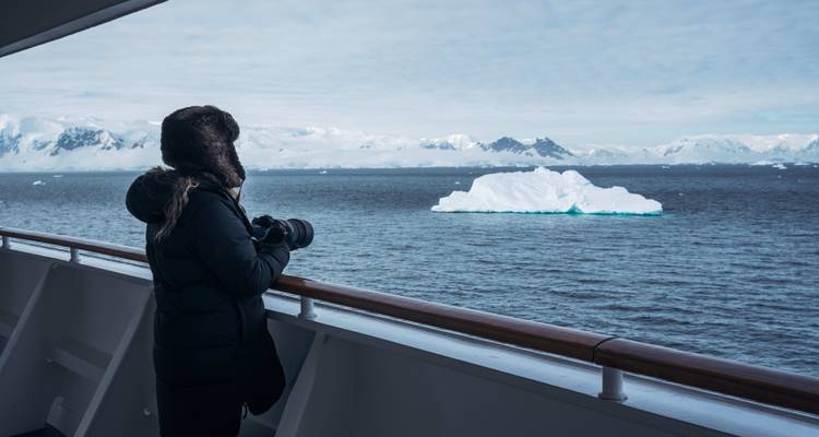 Une personne regardant des icebergs depuis le pont d'un navire.