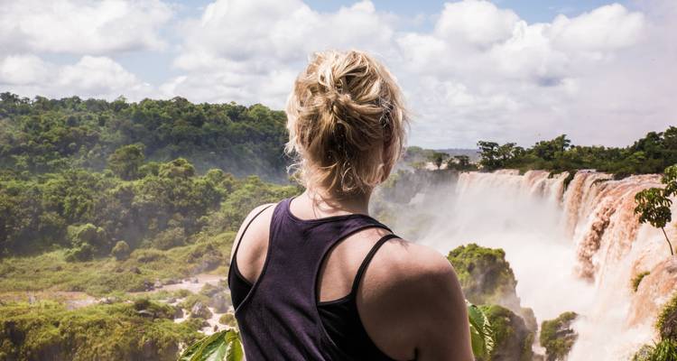 Personne contemplant les chutes d'Iguazu avec une végétation luxuriante tout autour.
