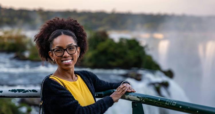 Femme souriante avec les chutes d'Iguazu en arrière-plan.