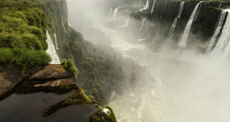 Vue depuis le sommet d'une cascade qui dévale vers des profondeurs brumeuses.