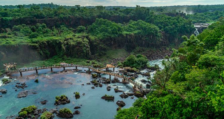 Des touristes marchant sur une passerelle au-dessus de l'eau aux chutes d'Iguazu.