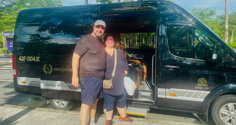 Deux personnes debout devant un van noir avec un paysage pittoresque en arrière-plan.