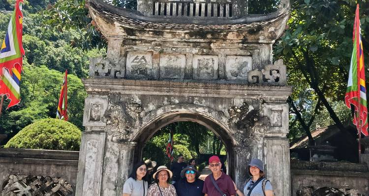 Los viajeros se reúnen bajo una antigua puerta de piedra decorada con tallados y banderas.