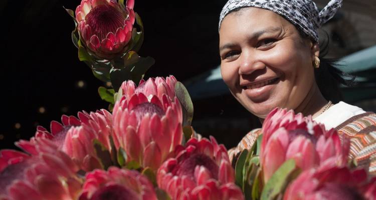 Frau lächelt neben einem Blumenstrauß.