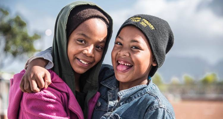 Zwei lächelnde Kinder posieren fröhlich.