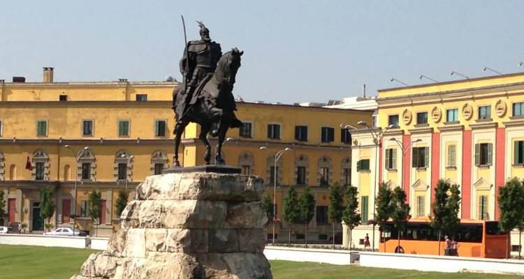 Reiterstatue des Skanderbeg, die sich über Tiranas Hauptplatz und gelbe Gebäude erhebt.