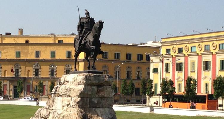 Ruiterstandbeeld voor een geel historisch gebouw.