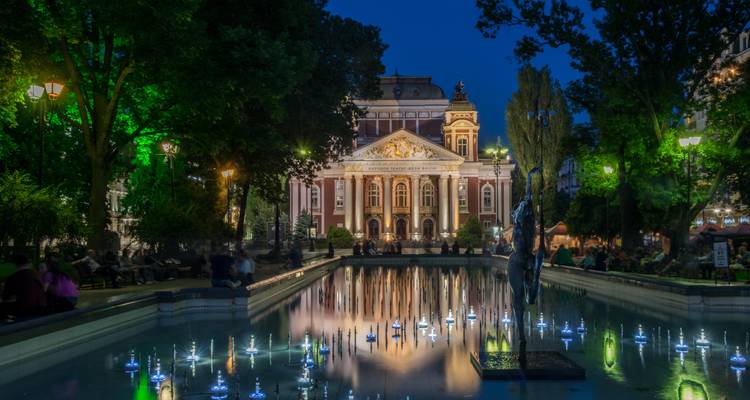 Nationaal Theater in Sofia verlicht 's nachts met een reflecterend waterelement.