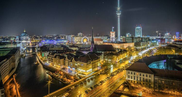 Stadsskyline bij nacht met helder verlichte gebouwen en een TV-toren.