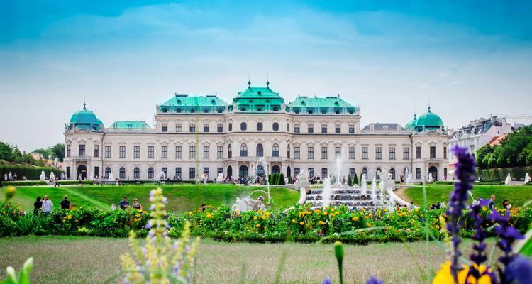Historischer Palast mit grünen Kupferdächern, umgeben von einem Garten.