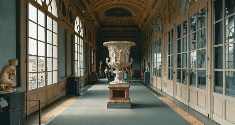 Une galerie élégante avec une urne centrale et des sculptures le long des côtés.