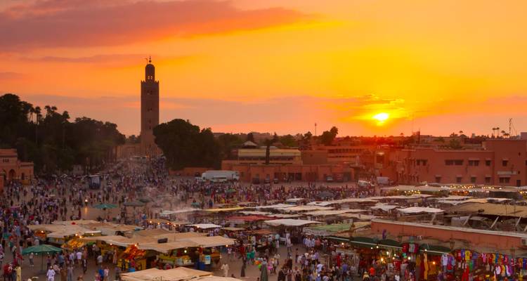 Vue du coucher de soleil sur un marché animé avec une tour de mosquée.