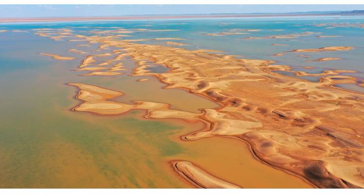 Vue aérienne d'un paysage sablonneux se transformant en eau.