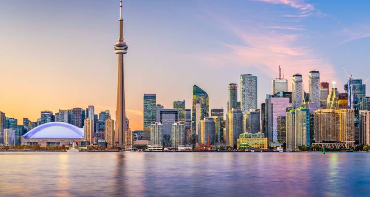 Iconic skyline with CN Tower reflecting in water.