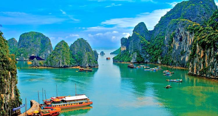 Vibrant waterscape with boats and limestone cliffs under a bright sky.