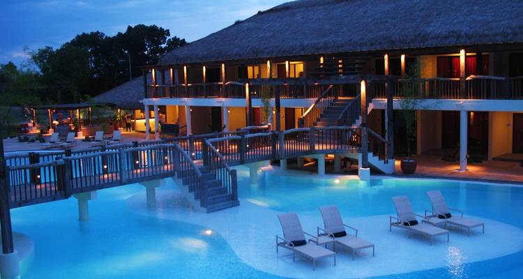 Elegantes Resort mit Brücke über beleuchteten Swimmingpool in der Dämmerung