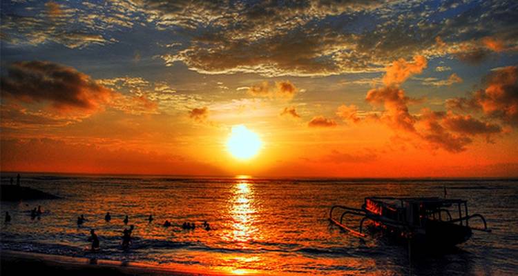 Magnifique coucher de soleil sur l'océan avec la silhouette de personnes qui nagent.