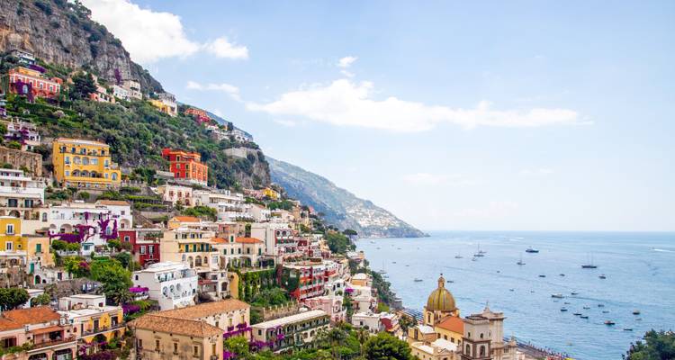 Colorful cliffside village of Positano cascading toward the sparkling Mediterranean Sea dotted with boats.