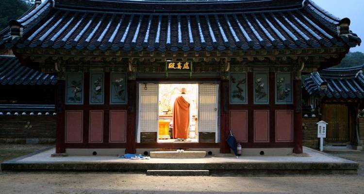 Un monje dedicado a la oración dentro de un templo coreano tradicional.