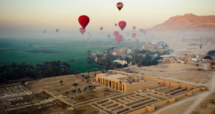 Heißluftballons über einer Wüstenlandschaft mit Tempeln.