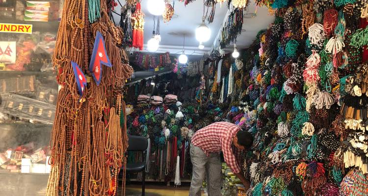Marktkraam met kleurrijke kralen en Nepalese vlaggen, persoon die koopwaar rangschikt.