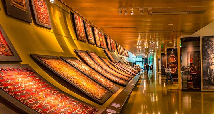 Hileras de alfombras azerbaiyanas ornamentadas exhibidas a lo largo de paredes inclinadas dentro del moderno Museo de Alfombras.