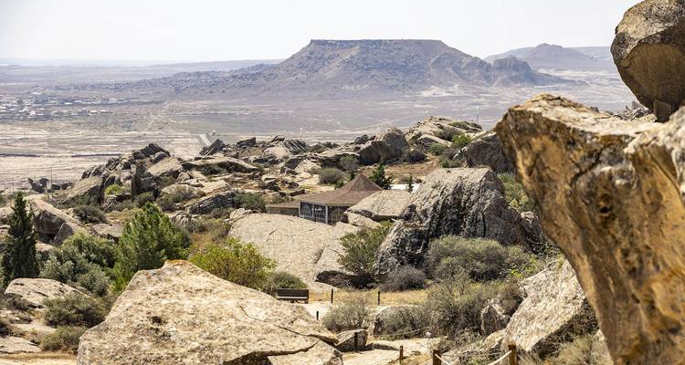 Paisaje desértico rocoso con rocas dispersas y colinas de cima plana en la distancia en el Parque Nacional de Gobustán.