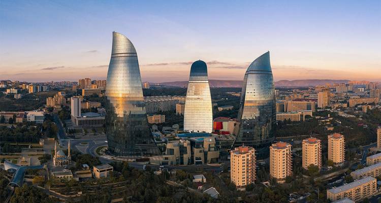 Vista aérea del amanecer de las icónicas Torres de la Llama resplandeciendo sobre el paisaje urbano de Bakú.