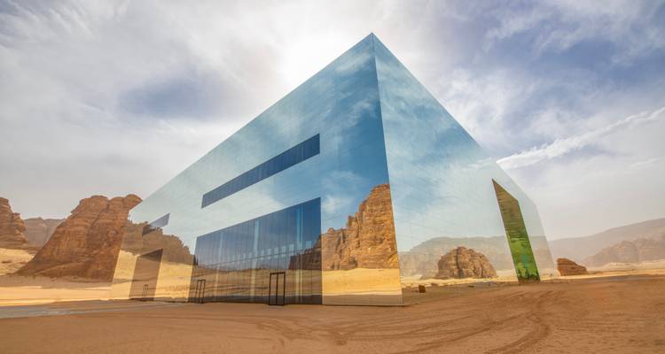 Ein modernes reflektierendes Gebäude inmitten einer Wüstenlandschaft.