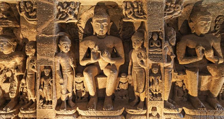 Statues anciennes en pierre sculptées de manière complexe représentant des figures disposées en rangée.