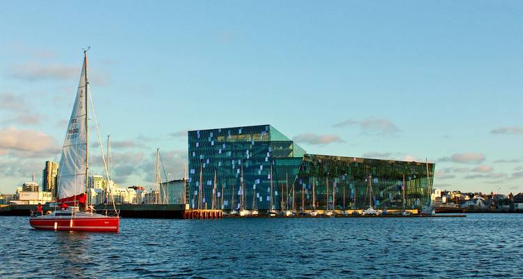 Bâtiment moderne au bord de l'eau avec des voiliers.