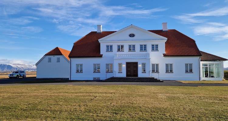 Maison blanche avec un toit rouge dans un champ herbeux.
