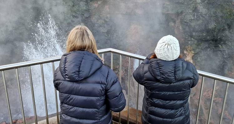 Deux personnes observant une activité géothermique fumante.