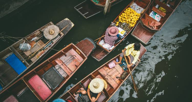 Botes coloridos en un mercado flotante con personas compartiendo mercancías.