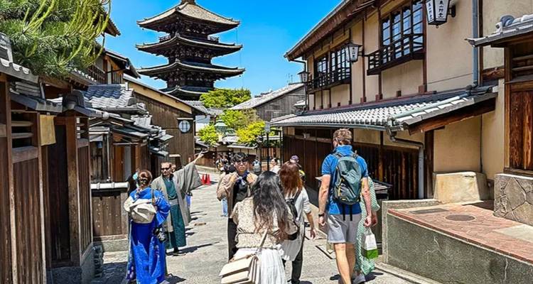Bezoekers lopen over een historische laan richting de Yasaka Pagoda tussen traditionele houten stadshuizen op een zonnige dag.