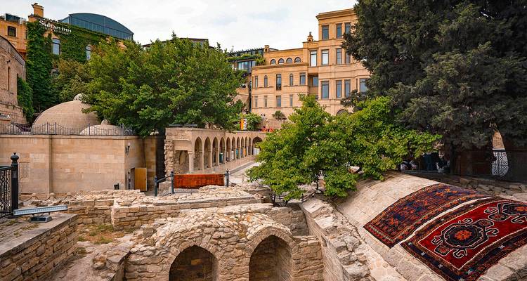 Arcs de pierre, cours et bâtiments traditionnels entrelacés de verdure dans la Vieille Ville de Bakou.