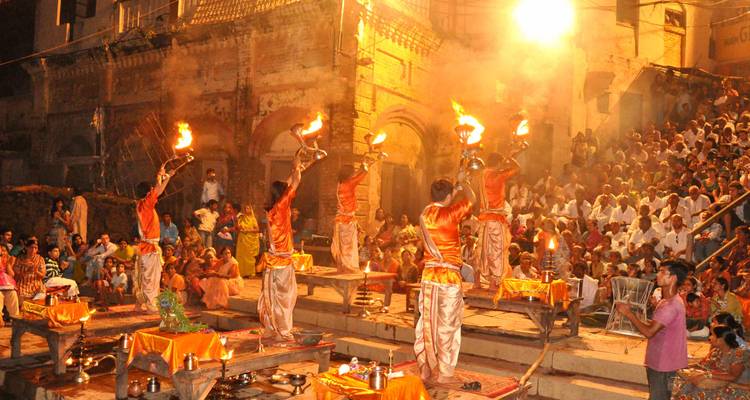Evening ritual with people holding torches in a spiritual setting.