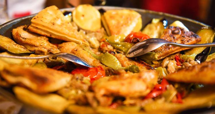 Bunte Platte mit gebratenem Hähnchen, Gemüse und Fladenbrot-Stücken, serviert im Familienstil.
