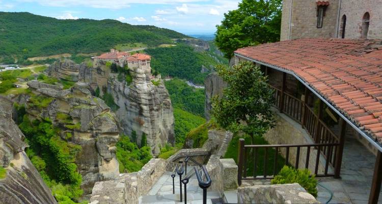 Un monastère perché au sommet d'un rocher avec une vue panoramique sur les montagnes environnantes.