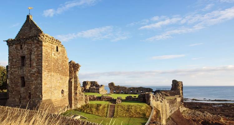 Die Steinruinen von St Andrews Castle überblicken die Nordsee unter einem blauen Himmel.