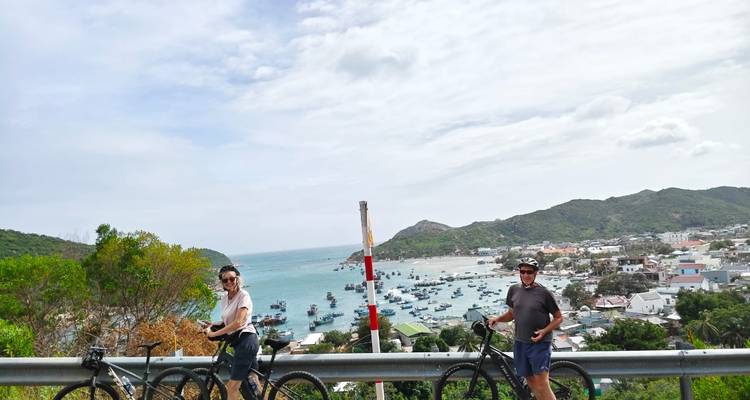 Cyclistes avec une vue côtière panoramique et une ville en arrière-plan.