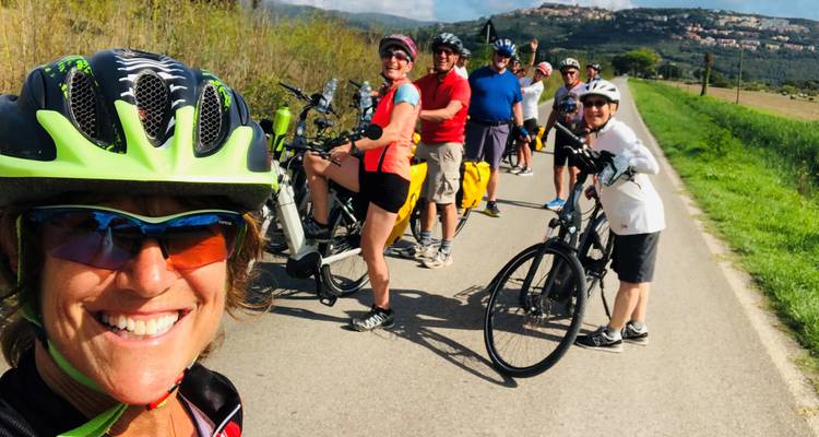 Groupe de cyclistes souriants posant avec leurs vélos sur une route rurale.
