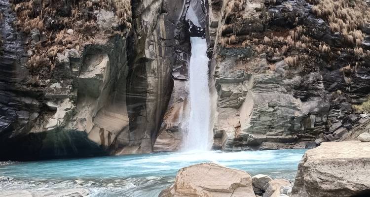 Cascada que desciende por un acantilado rocoso hasta un estanque.