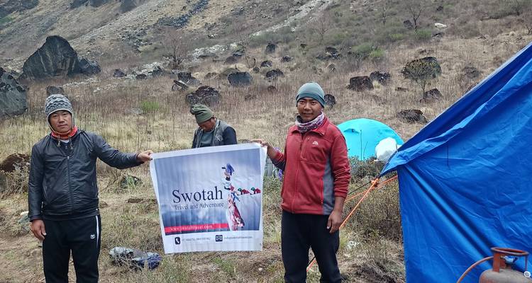 Tres personas sosteniendo una pancarta en un área de campamento.