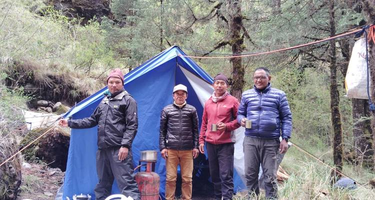 Cuatro personas posando frente a una tienda de campaña en un entorno boscoso.