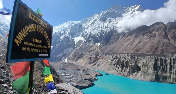 Montañas y un lago con un letrero que indica Campo Base Annapurna.