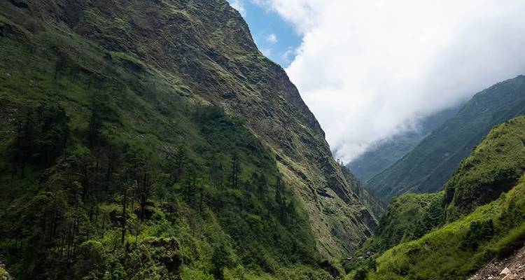 Valle verde empinado bajo un cielo nublado.