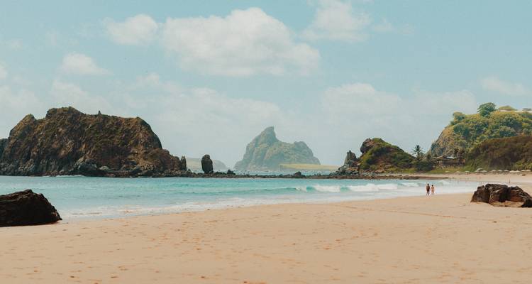 Plage de sable avec des rochers et vues lointaines sur les îles.